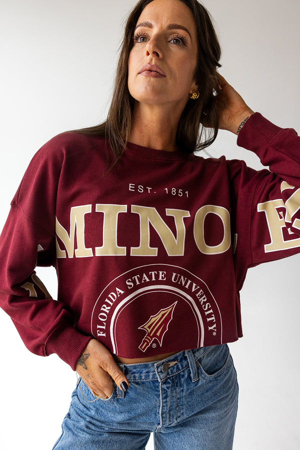 Woman wearing a Florida State University sweatshirt with gold lettering on a plain background