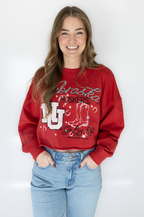 Person wearing a red sweatshirt with graphics and text, standing against a white background
