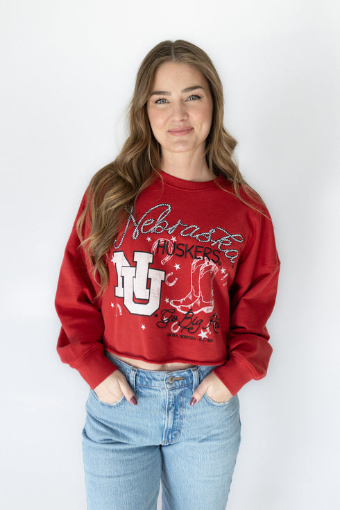 Person wearing a red 'Nebraska Huskers' sweatshirt with a white background