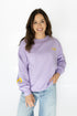 Woman wearing a purple sweatshirt with yellow accents on a white background