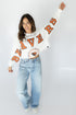 Person wearing a white long-sleeve shirt with orange text and blue jeans on a plain background