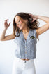 Woman wearing a gray cable knit vest with a logo on a white background