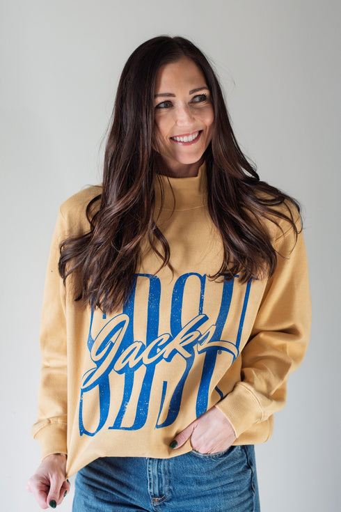 Woman wearing a tan sweatshirt with blue text on a plain background