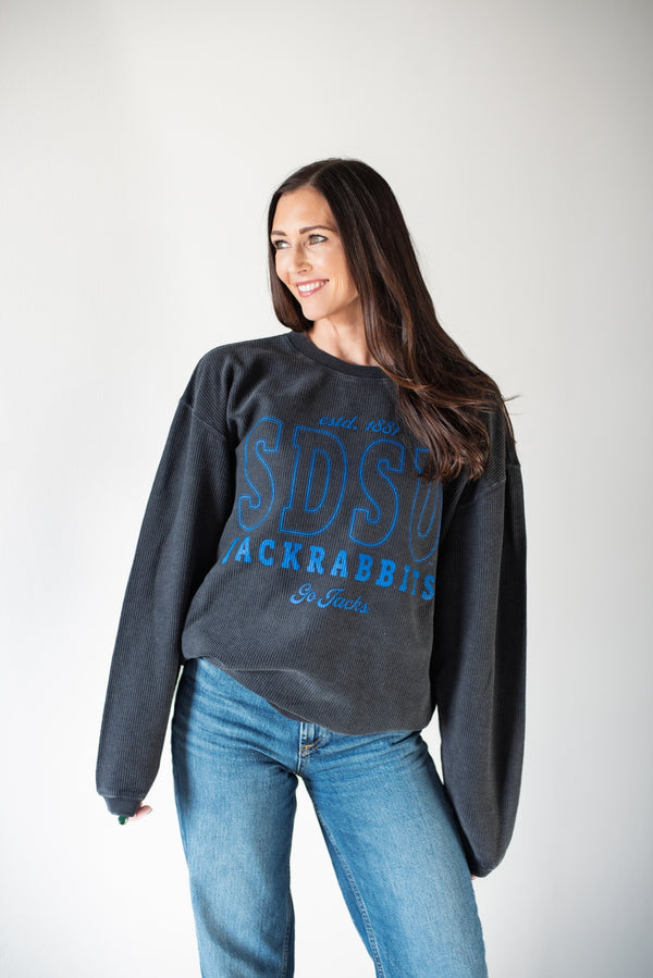 Woman wearing a dark gray sweatshirt with blue text and jeans on a white background